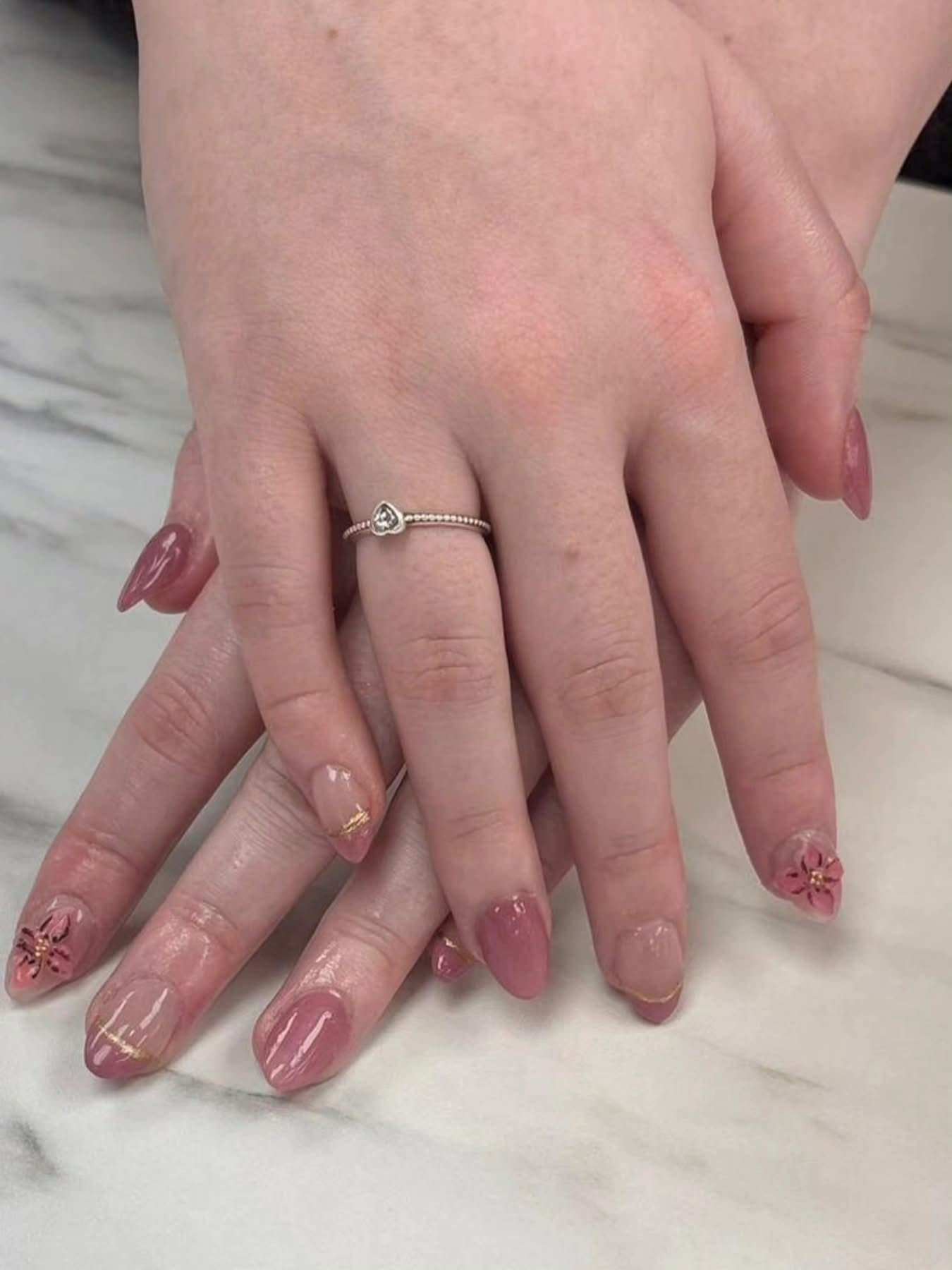 Soft pink and burgundy almond nails with floral nail art and gold foil details at Ash's Lashes and Esthetics