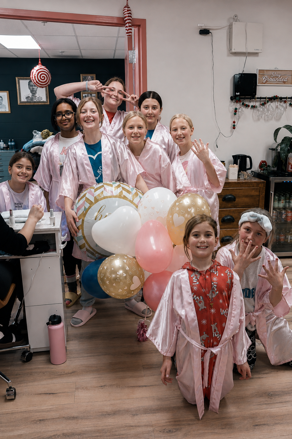 Group of girls in pink satin robes celebrating a birthday party at Ash's Lashes with balloons