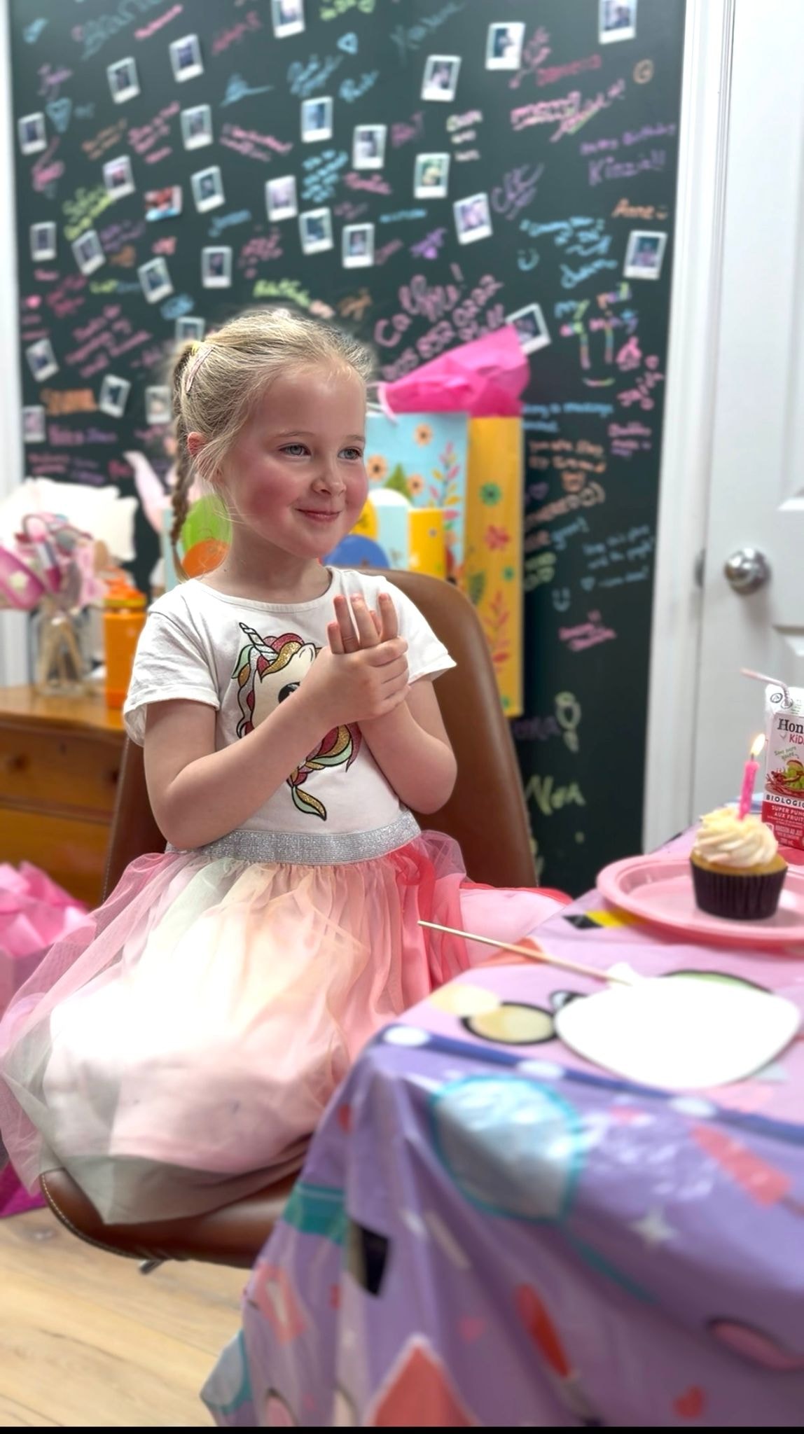 Little girl in a pink tutu dress smiling at her birthday party at Ash's Lashes with a cupcake and candle