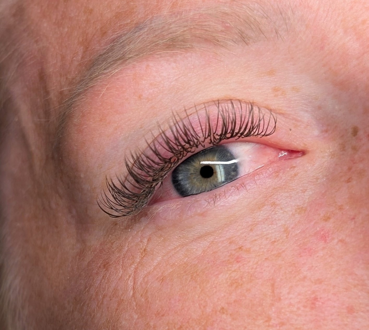 Close-up of classic single lash extensions on grey-green eyes at Ash's Lashes and Esthetics