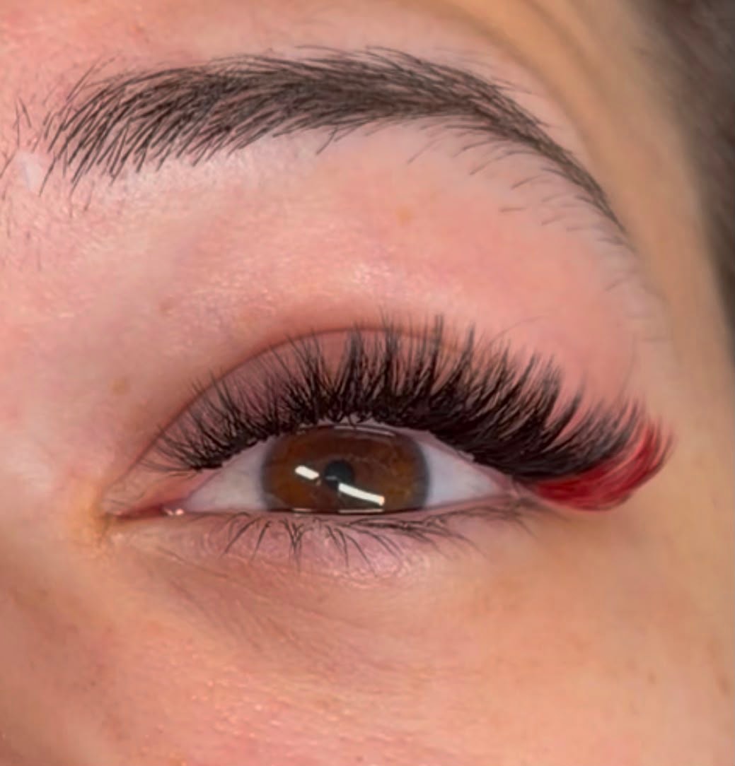 Close-up of volume lash extensions with a pop of red colour on brown eyes at Ash's Lashes and Esthetics